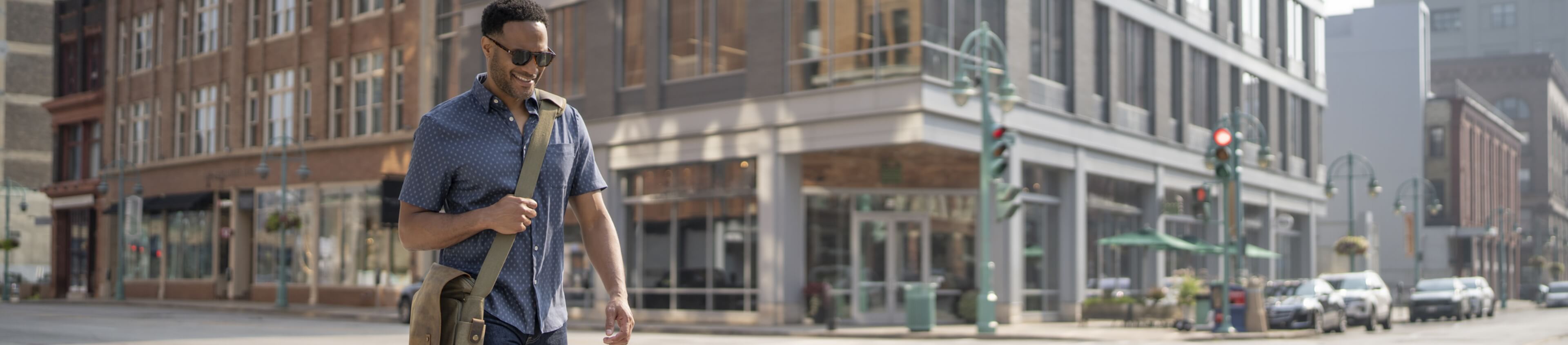 Image features a man walking through the city wearing business casual attire.