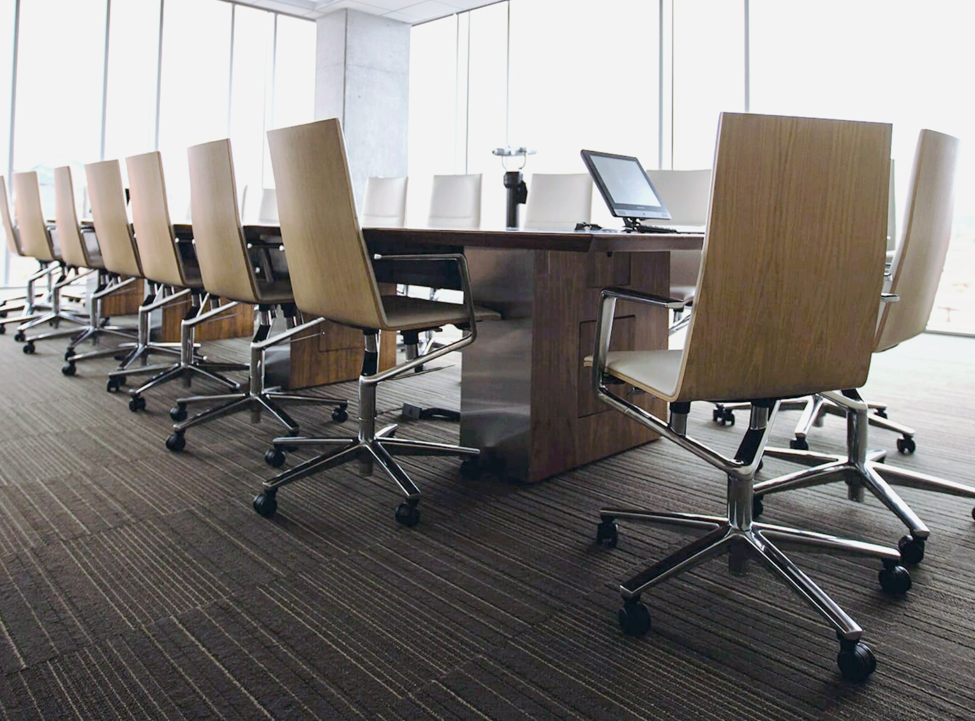 Image features a boardroom with a long table with chairs.